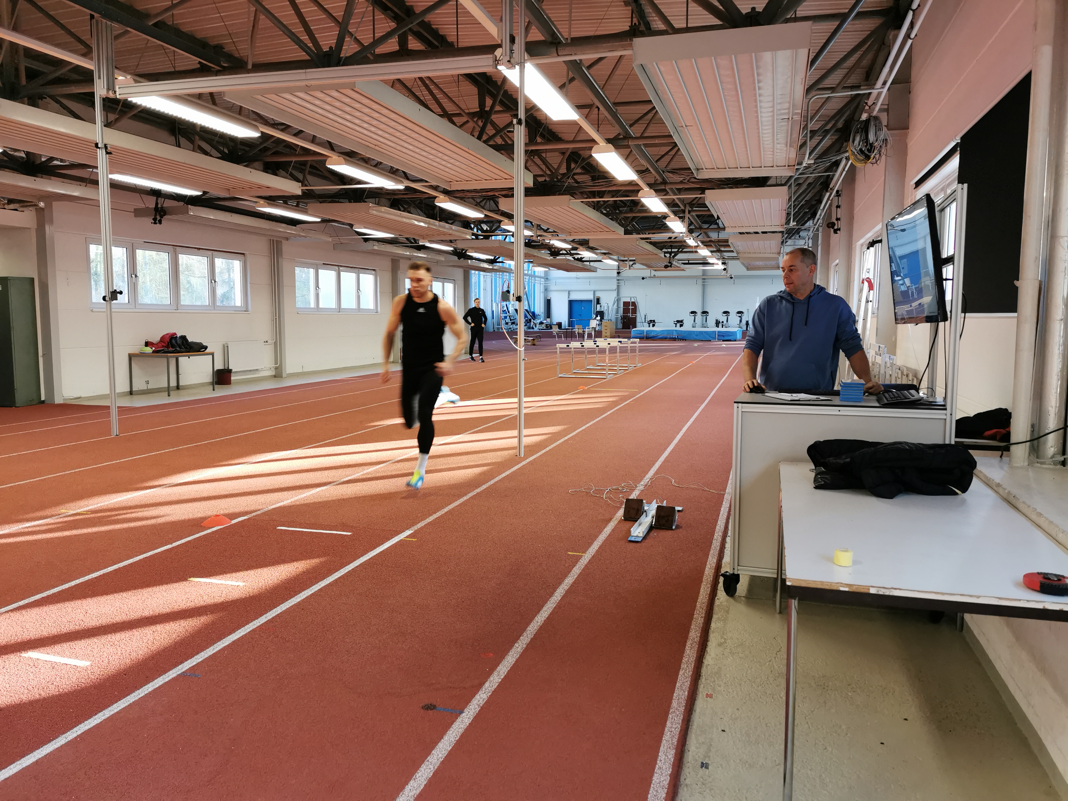 Ein Sprinter läuft auf einer Sprintbahn, unter der digitale Kraftmessplatten installiert sind. 